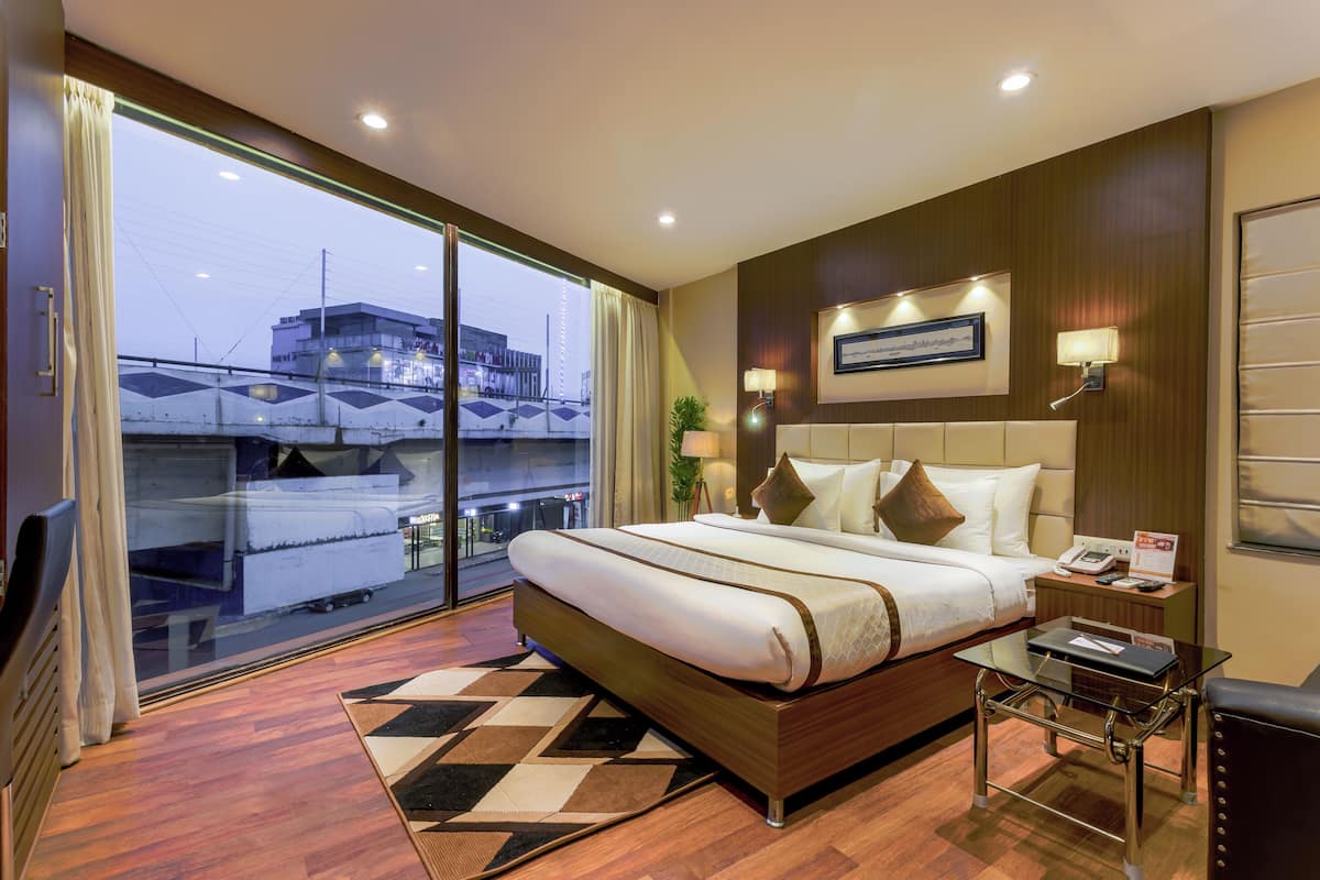 Une chambre d’hôtel avec un grand lit, une table en verre, une table de chevet et une vue sur le paysage urbain.