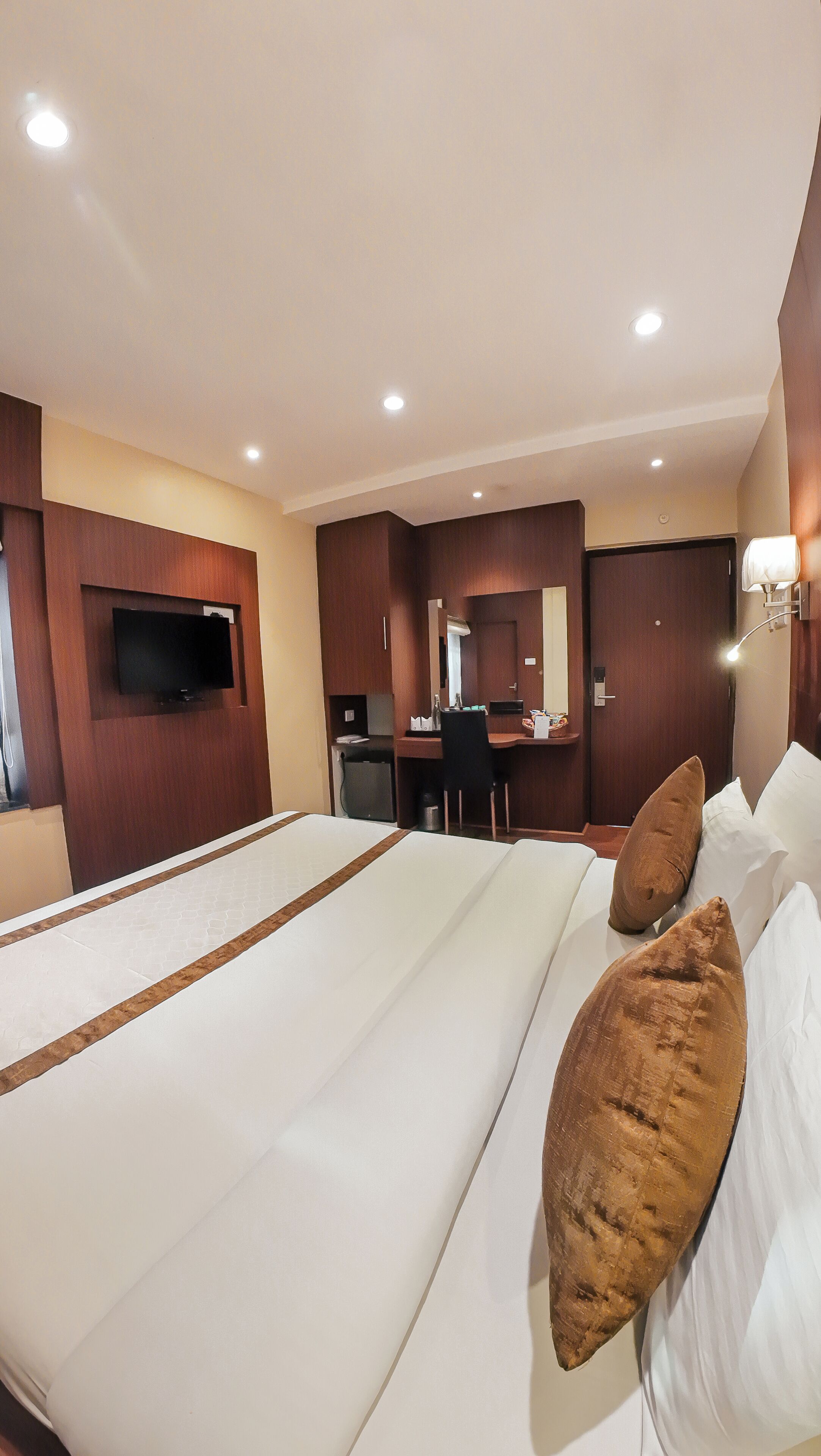 Una habitación de hotel con una cama grande, un escritorio, un televisor y un espejo.