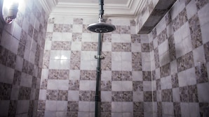 A shower with a vertical rain showerhead, tiled walls with a checkered pattern, and a light fixture on the left. - Ikeja Transit Hotel (Lagos)