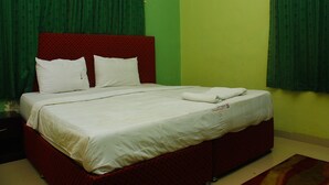 A bed with a red headboard, white bedding, and a green curtain. - Ikeja Transit Hotel (Lagos)