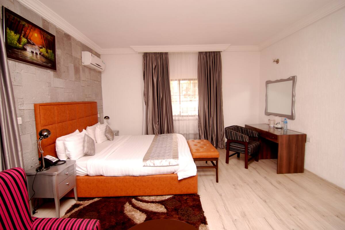 Ein Schlafzimmer mit Bett, Schreibtisch, Stuhl, Nachttisch und Spiegel.