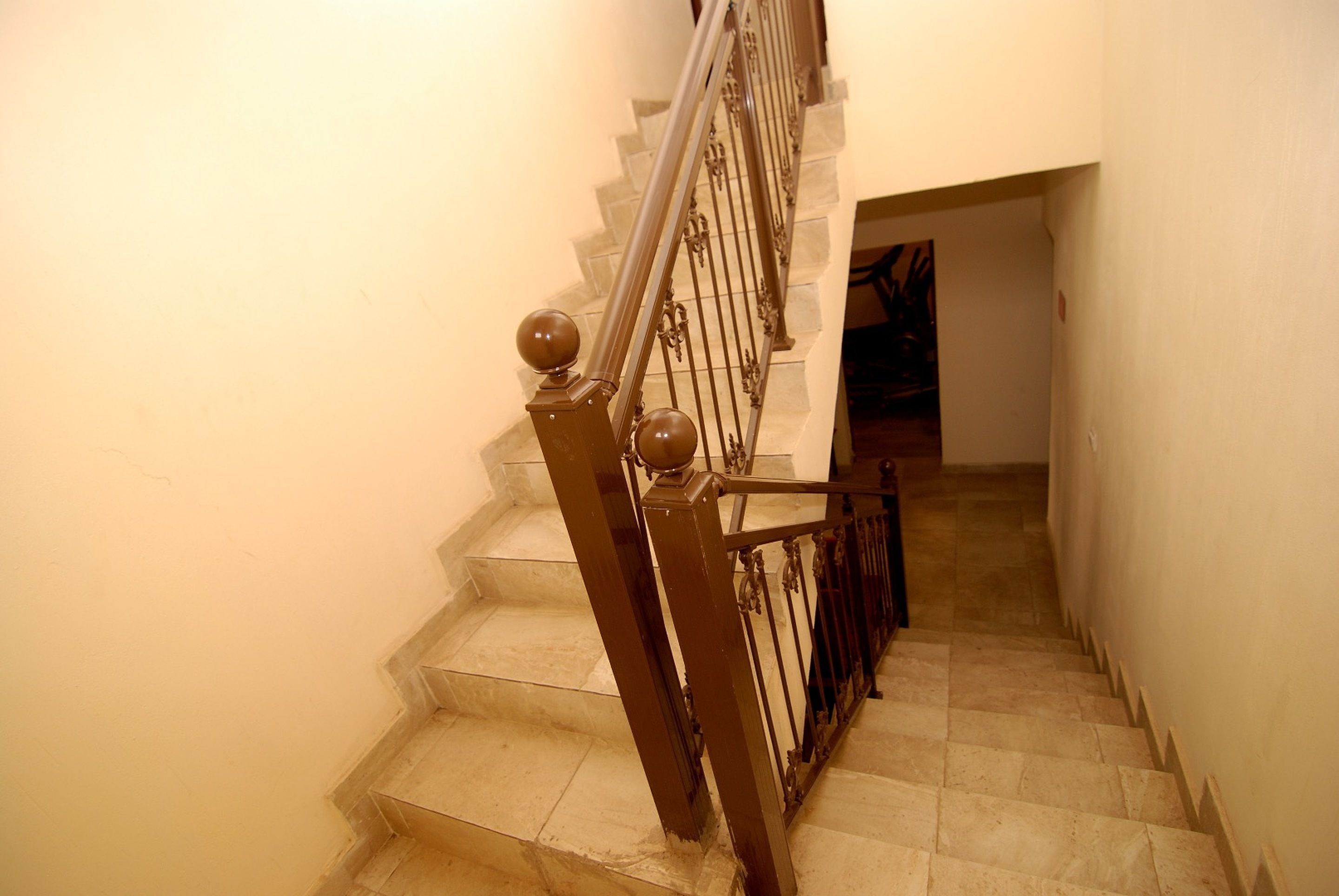 Una escalera con barandilla metálica y pasamanos, que sube a un piso superior.