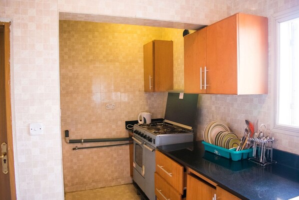 A compact kitchen with a gas stove, oven, and wooden cabinets.