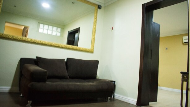 A room with a dark brown sofa, a large mirror with a gold frame, and a wooden door.
