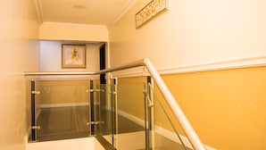 A staircase with glass railings and a yellow wall.
