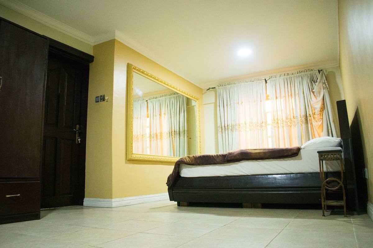 A bedroom with a bed, a large mirror, a wardrobe, and a television.