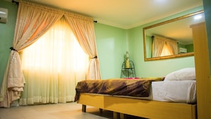 A bedroom with a bed, a mirror, and curtains.