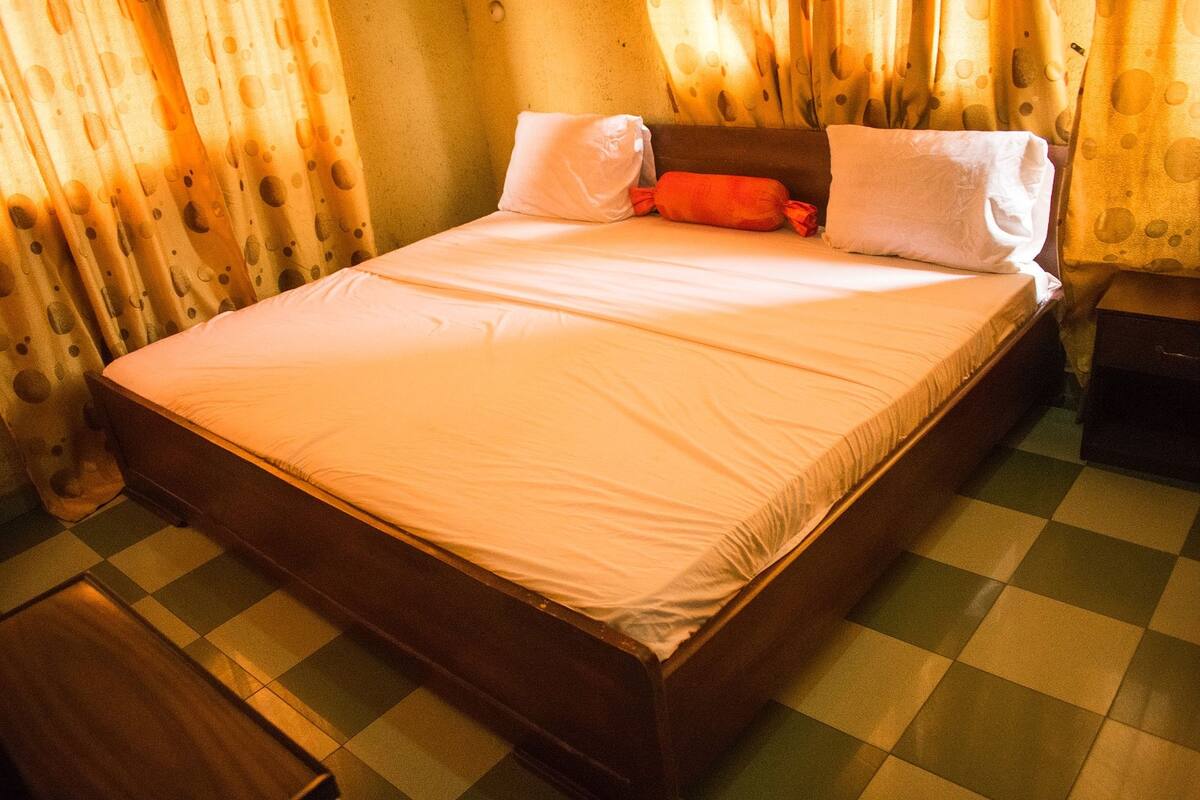 A bed with a checkered floor, a pillow, and a blanket.