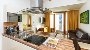 Una cocina moderna con horno empotrado, estufa y lavabo. Hay un comedor con mesa de madera y sofá de cuero marrón.