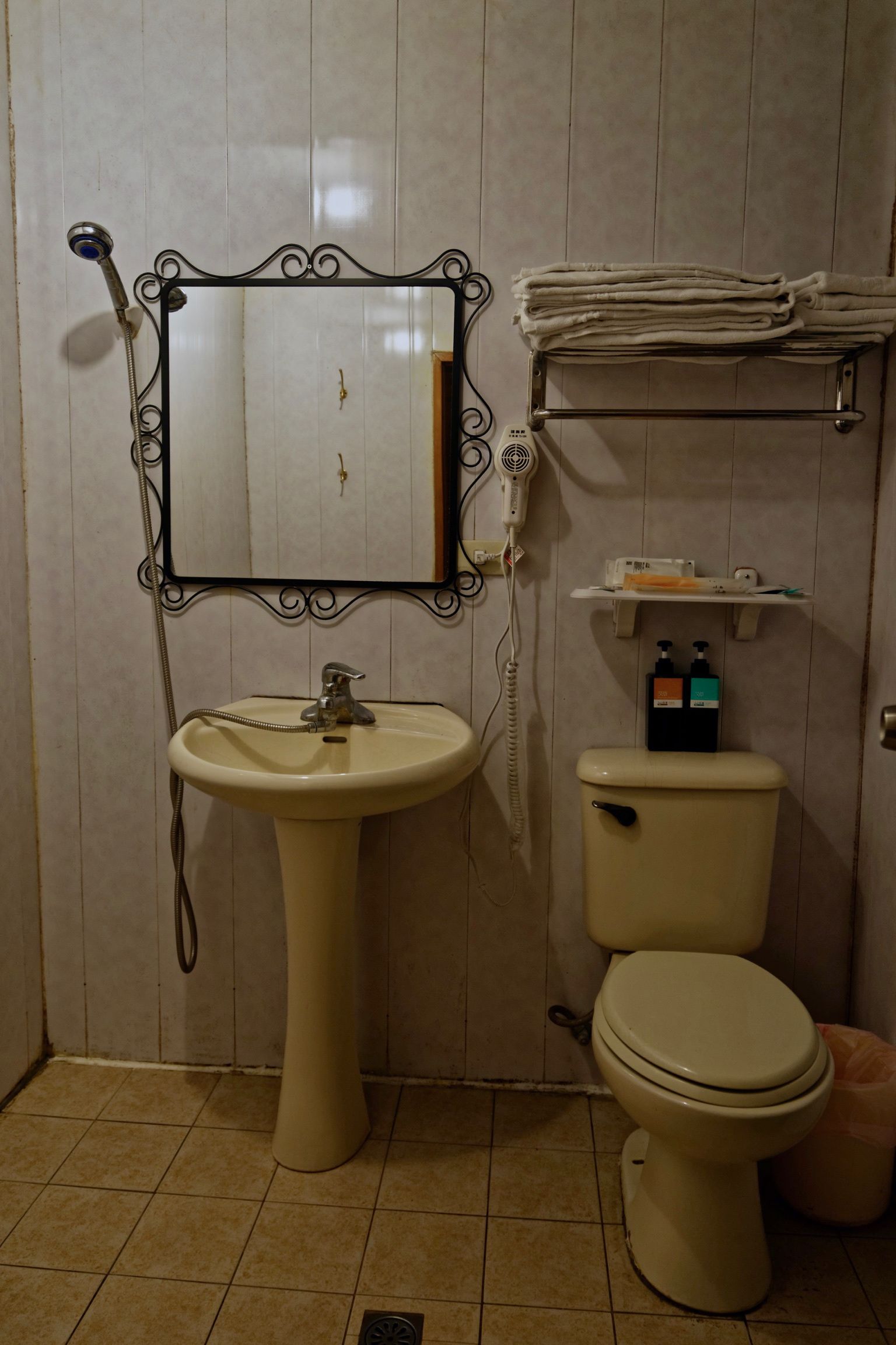 Un baño con lavamanos pedestal, inodoro y tocador con espejo.