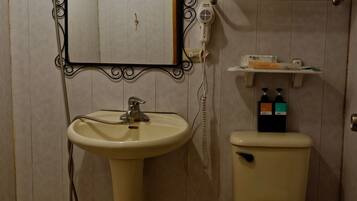 Un baño con lavamanos pedestal, inodoro y tocador con espejo.