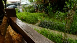 Un banco de madera con respaldo tallado, ubicado en un jardín exuberante con diversas plantas y un sendero.