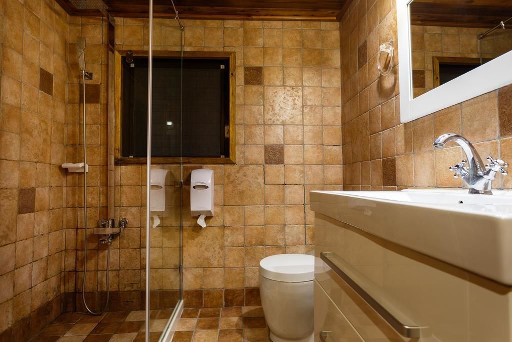 A bathroom with a shower, toilet, sink, and a window.