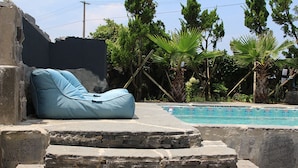 A stone pool with a blue bean bag chair and steps leading to it. - Void (Jeju City)