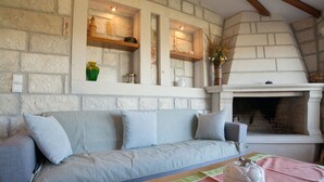 Una sala de estar acogedora con una pared de piedra, una chimenea, un sofá y un jarrón decorativo.