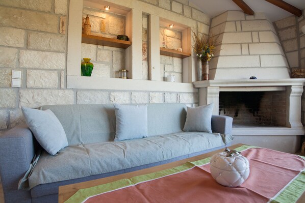 Un salon chaleureux avec un mur en pierre, une cheminée, un canapé et un vase décoratif.