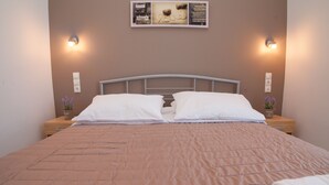 Una cama bien hecha con sábanas blancas, un edredón marrón y dos mesitas de noche con lámparas.