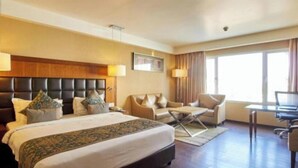Una habitación de hotel con una cama grande, un sofá, un escritorio y un televisor.