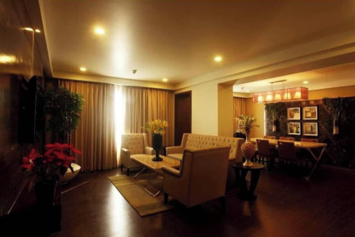 Um hall de hotel com sofá, cadeiras, área de refeições e balcão de recepção.
