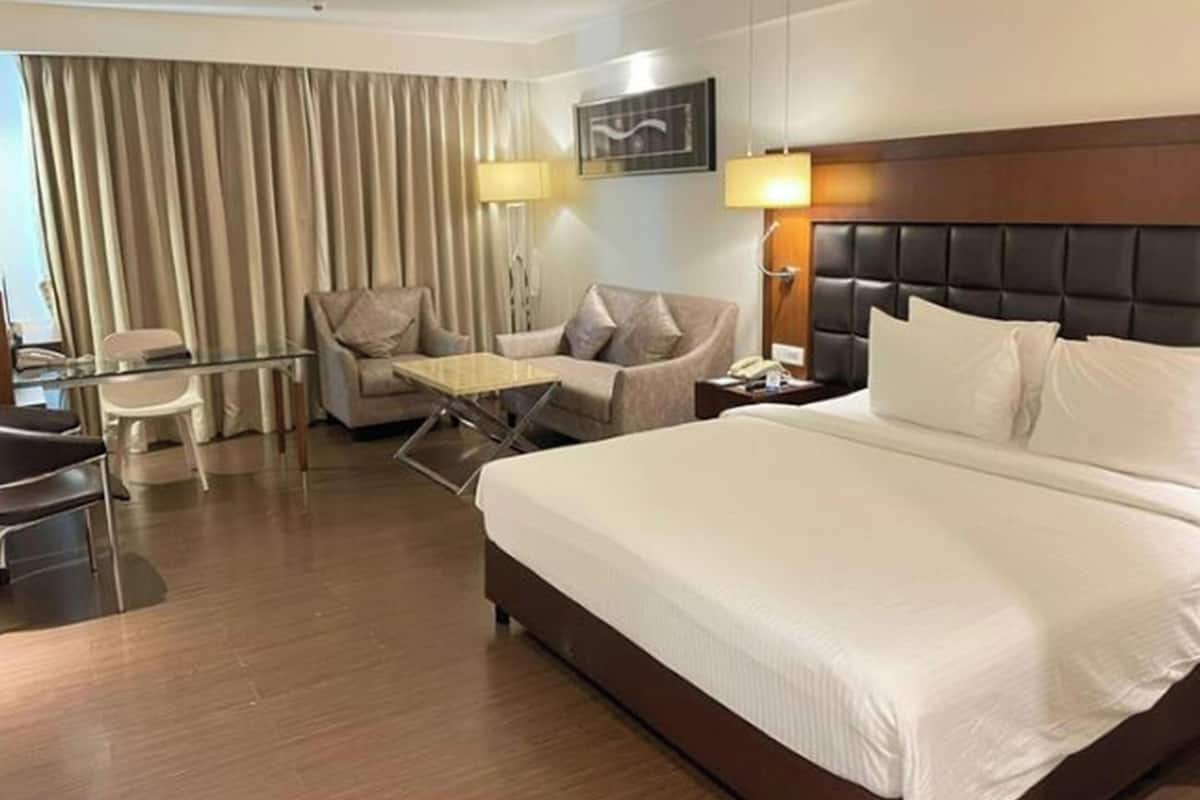Quarto de hotel com uma cama grande, um sofá, uma mesa e uma cadeira.