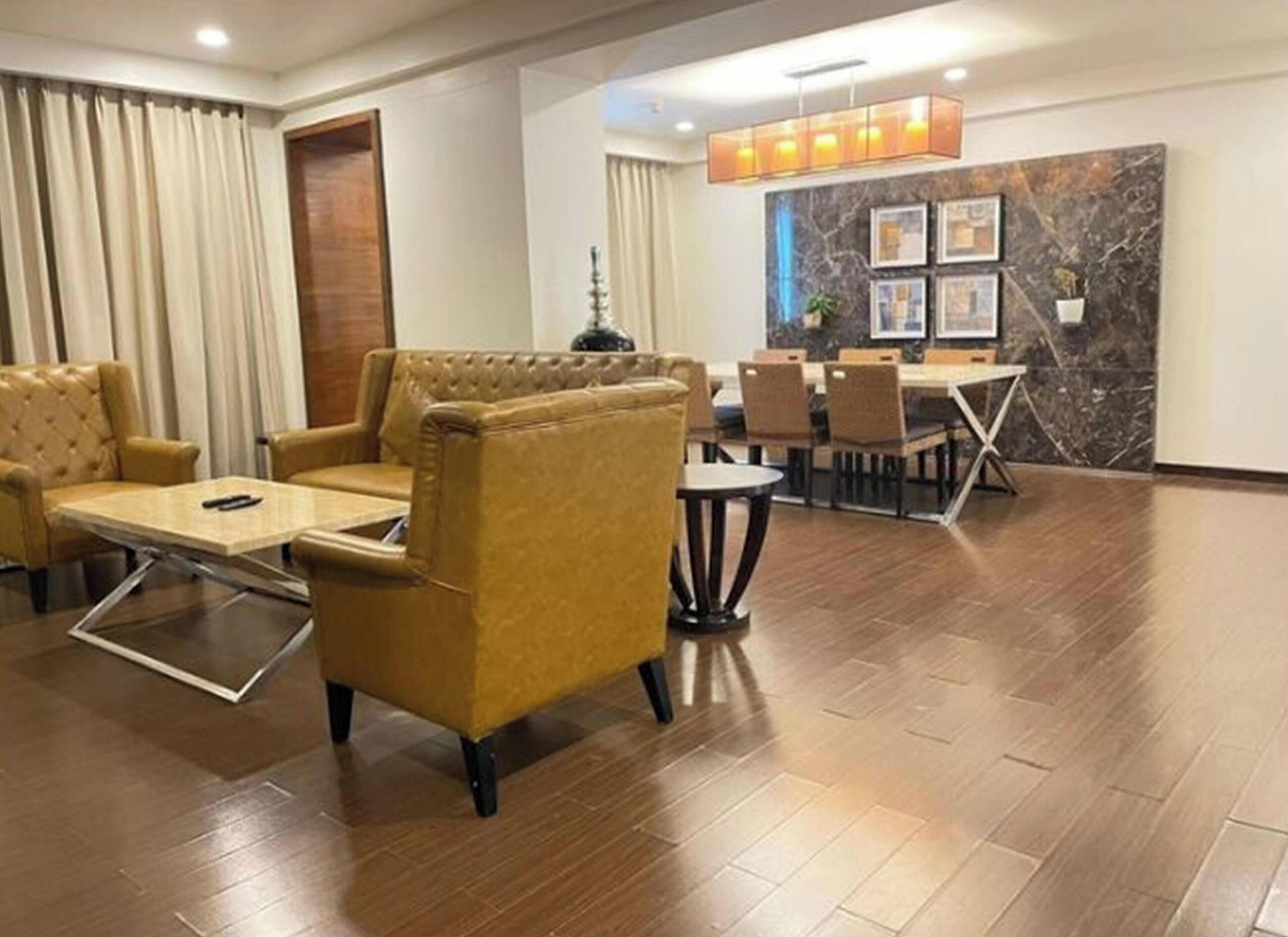 Un hall de hotel con zona de estar, una mesa de comedor y una pared de mármol con cuadros enmarcados.