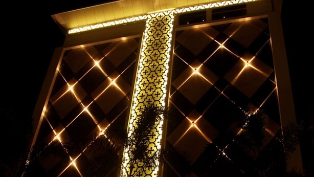 Un edificio con un panel luminoso vertical llamativo y un letrero que dice "Paradigm Sarovar Portico".