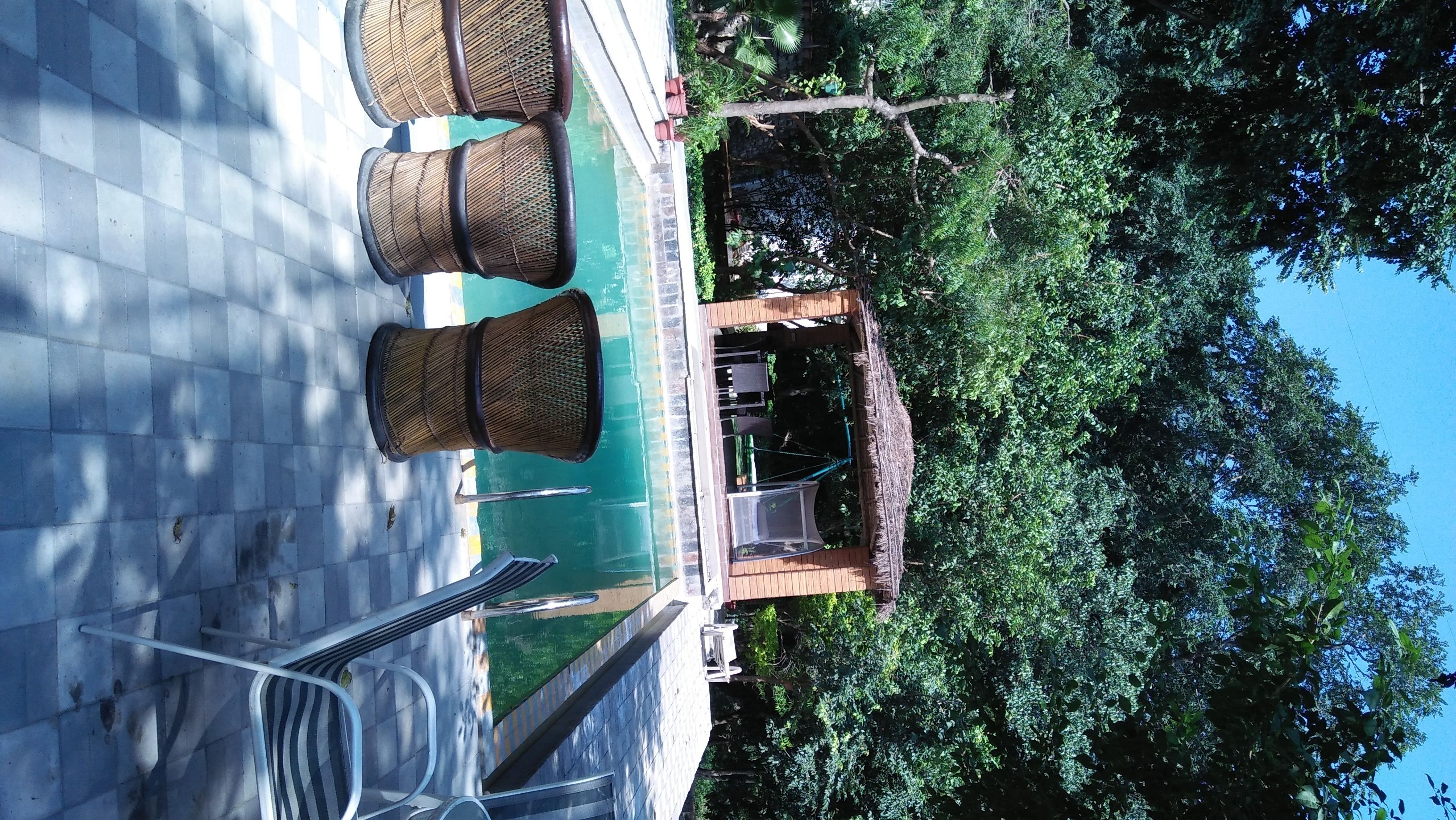 Un área de piscina con sillas de mimbre y un pabellón.