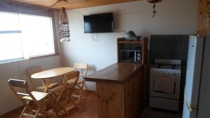 A compact kitchen with wooden cabinets, a microwave, a stove, and a dining area with a table and chairs.