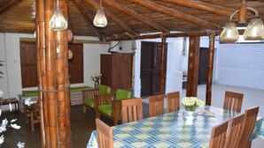 A dining area with a bamboo ceiling, wooden chairs, and a table with a checkered tablecloth.