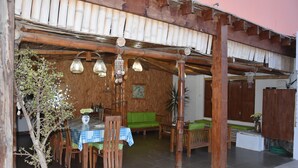 A wooden dining area with a table and chairs, a green sofa, and hanging lights.