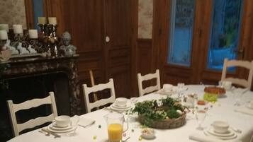 A dining area with a long table set for a meal, surrounded by wooden chairs.