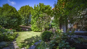 A garden with a stone pathway, lush greenery, and flowering plants. - Maison d'Hôtes Cap et Marais d'Opale (Saint-Omer)