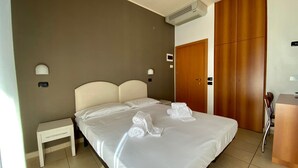 A hotel room with a large bed, a bedside table, a wardrobe, and a desk with chairs. - Hotel Berenice Rimini Mare (Rimini)