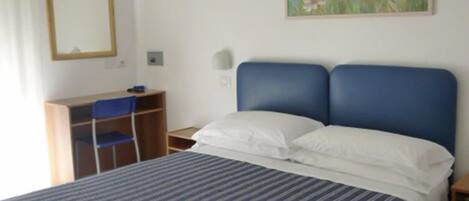 Un dormitorio con cama, escritorio, silla y un cuadro en la pared.