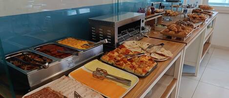 A buffet with various food options including meats, cheeses, and pastries.