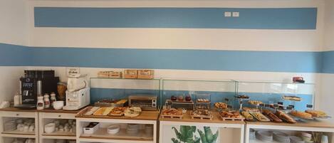 Um buffet de café da manhã com diversos alimentos e uma máquina de café.