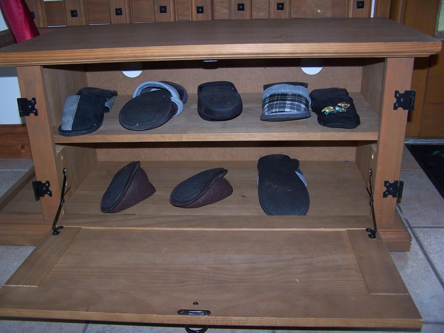 A wooden shoe rack with multiple shelves holding various pairs of shoes.
