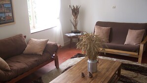 En stue med en brun sofa, et træbord og en vase med tørrede planter.