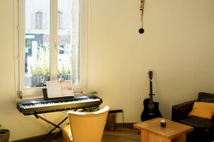 Une pièce avec un piano, une guitare, une table en bois et une chaise.