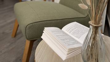 Un sofá verde con un libro abierto sobre una mesa de madera al lado.