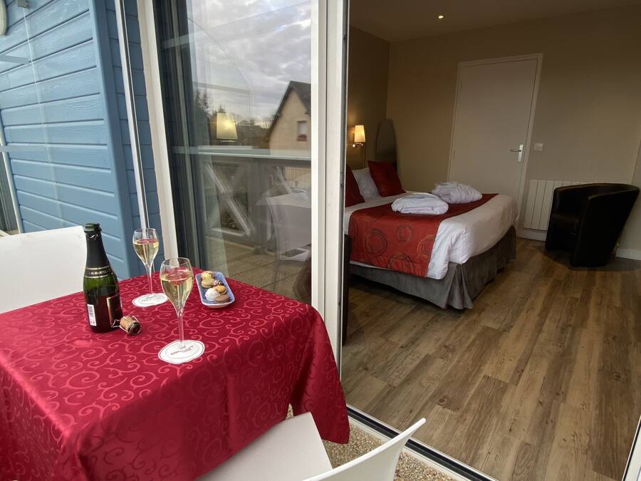 Et hotelværelse med en seng, et lille bord med en flaske og glas, samt udsigt ud