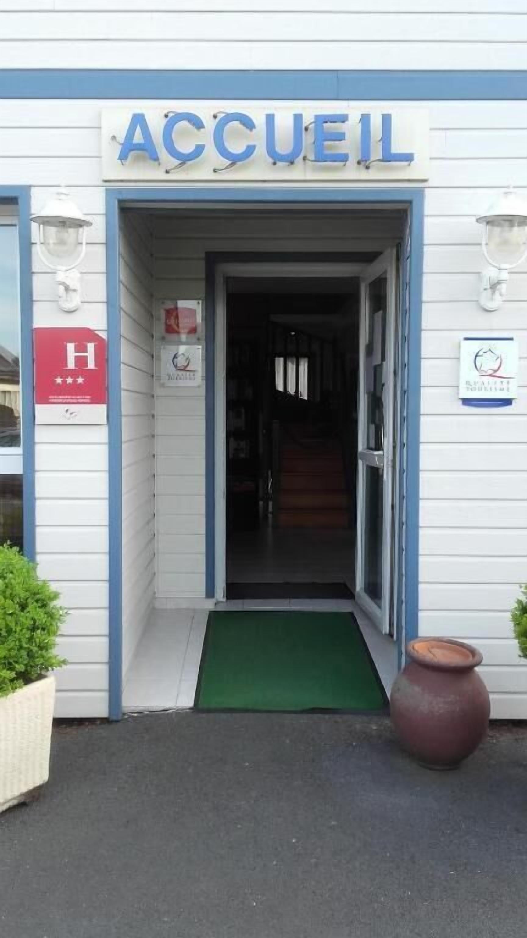 A building entrance with a sign reading "ACCUEL" and a red sign with a white 'H' indicating a hotel.