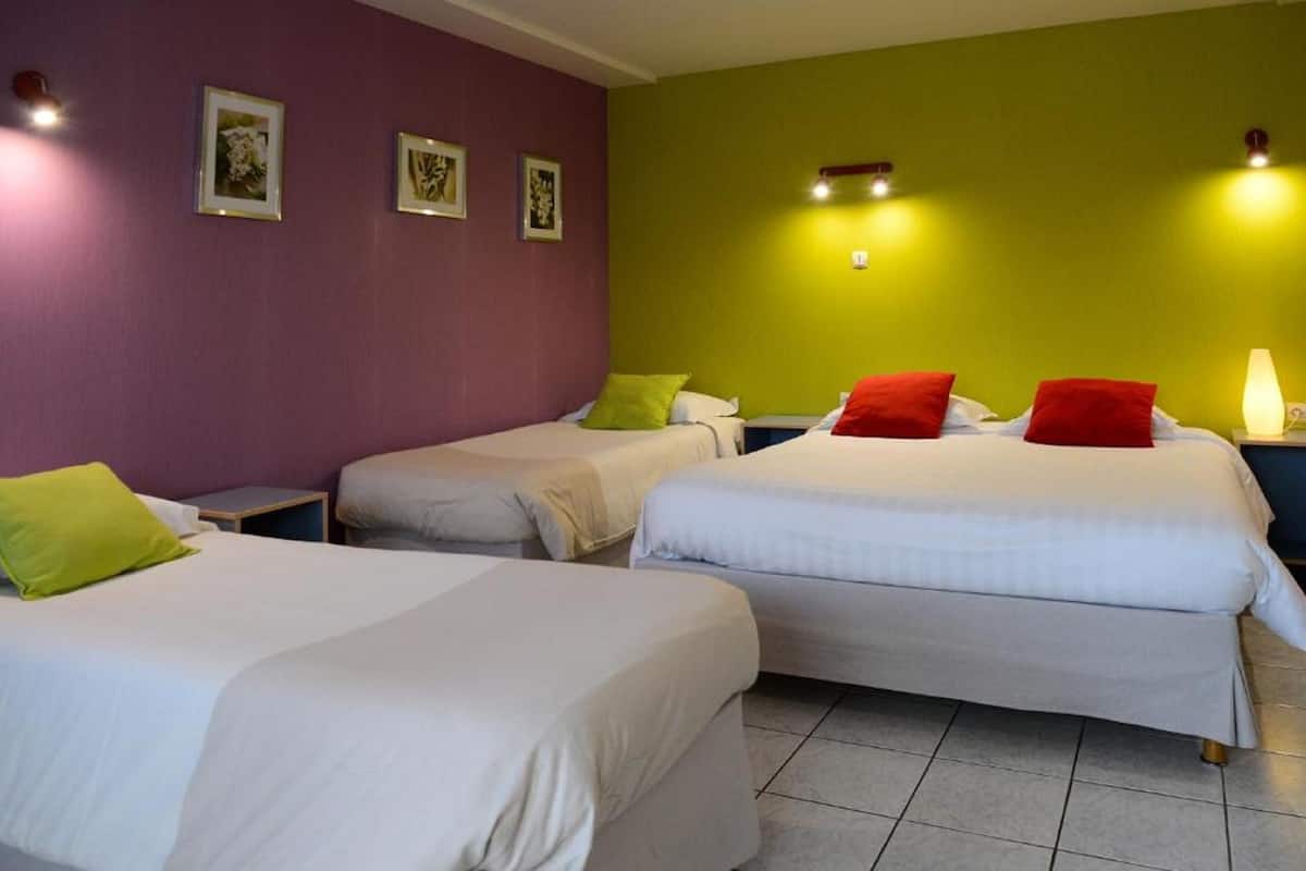 Ein Hotelzimmer mit drei Einzelbetten, jedes mit einem Kissen und einem Nachttisch.
