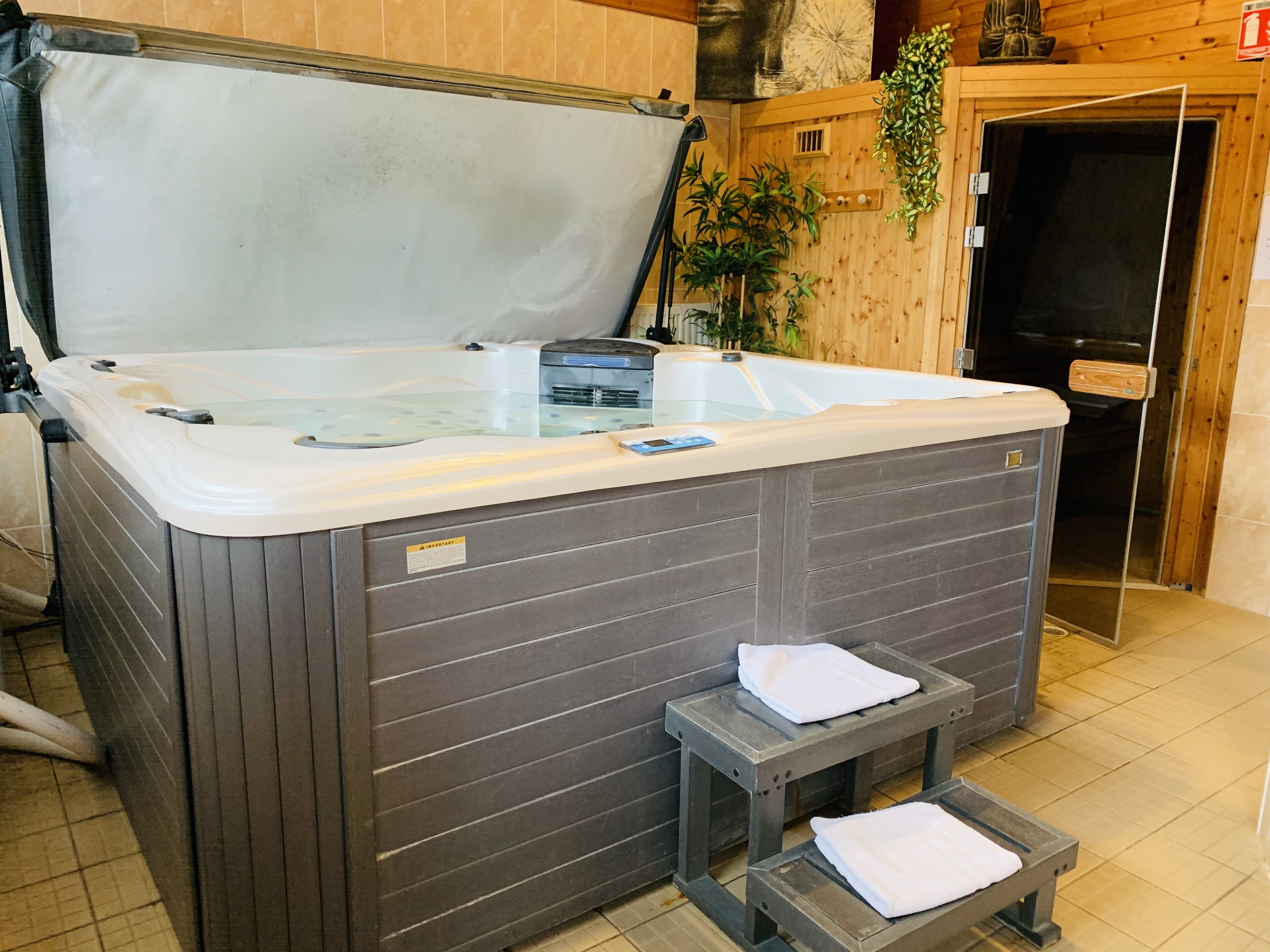 A hot tub with a glass top, a small step stool, and a towel on the step.