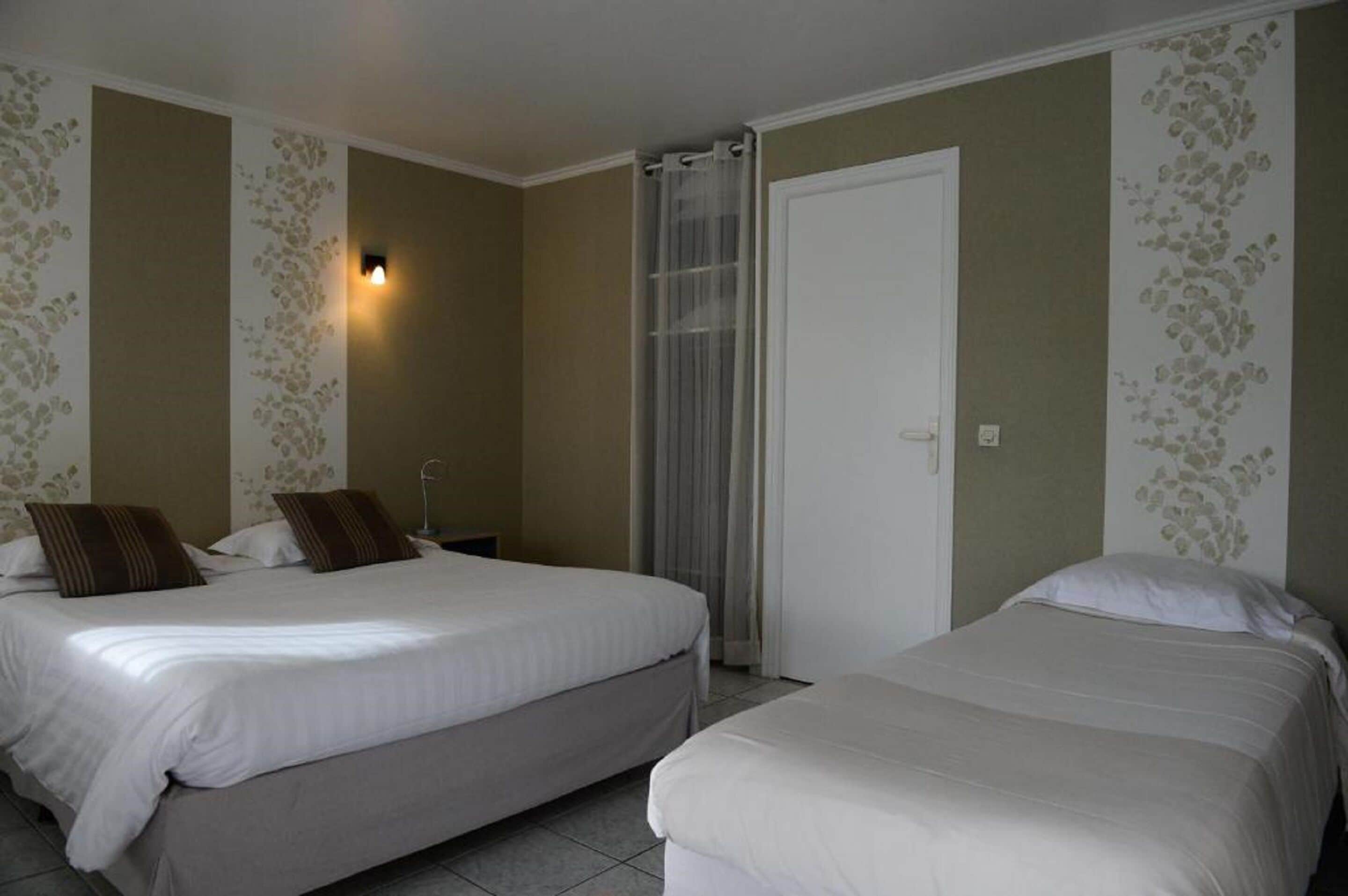 A hotel room with two beds, a bathroom, and a door.