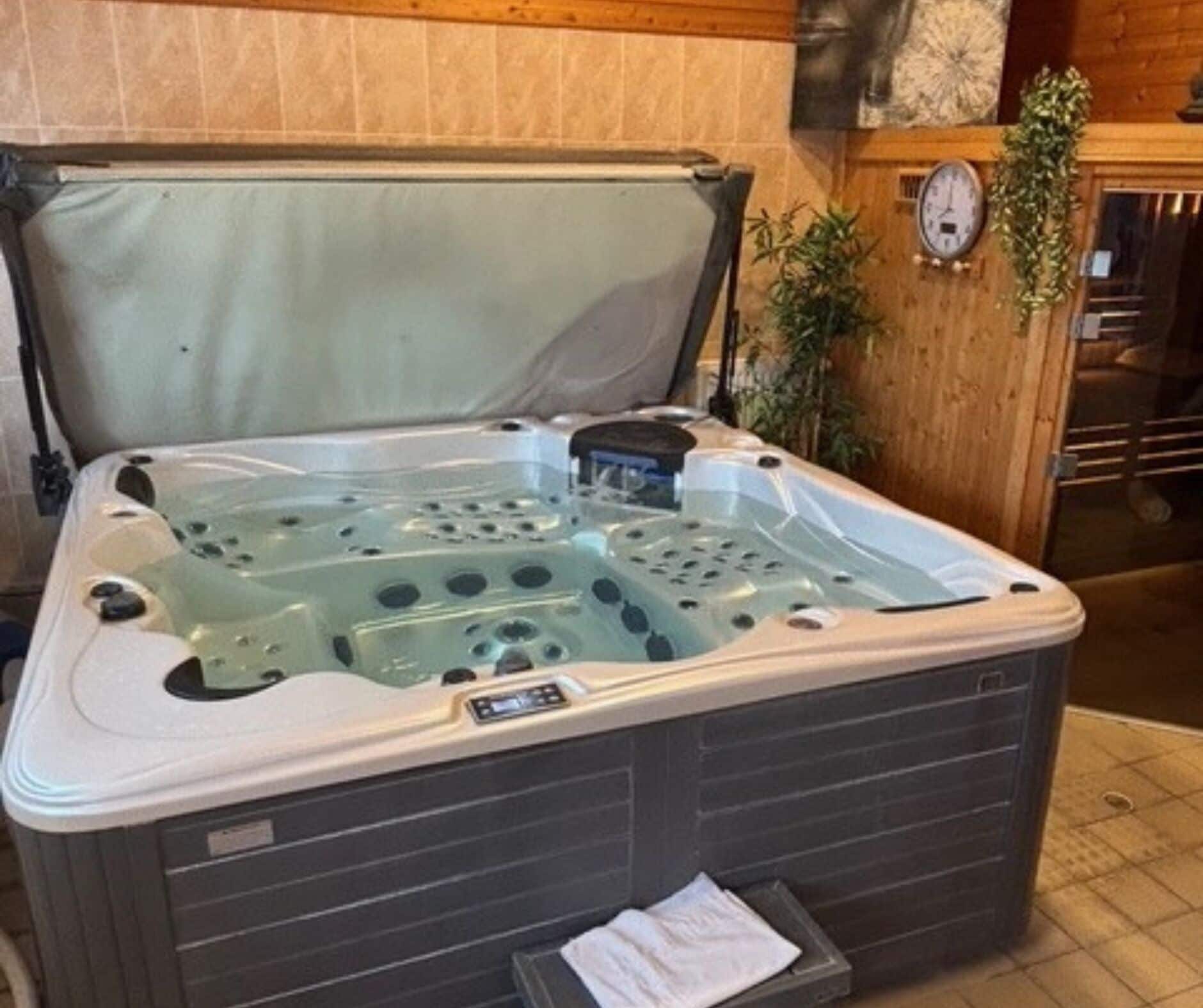 Ein Whirlpool mit Bedienfeld, Handtuchhalter und einer Uhr an der Wand.