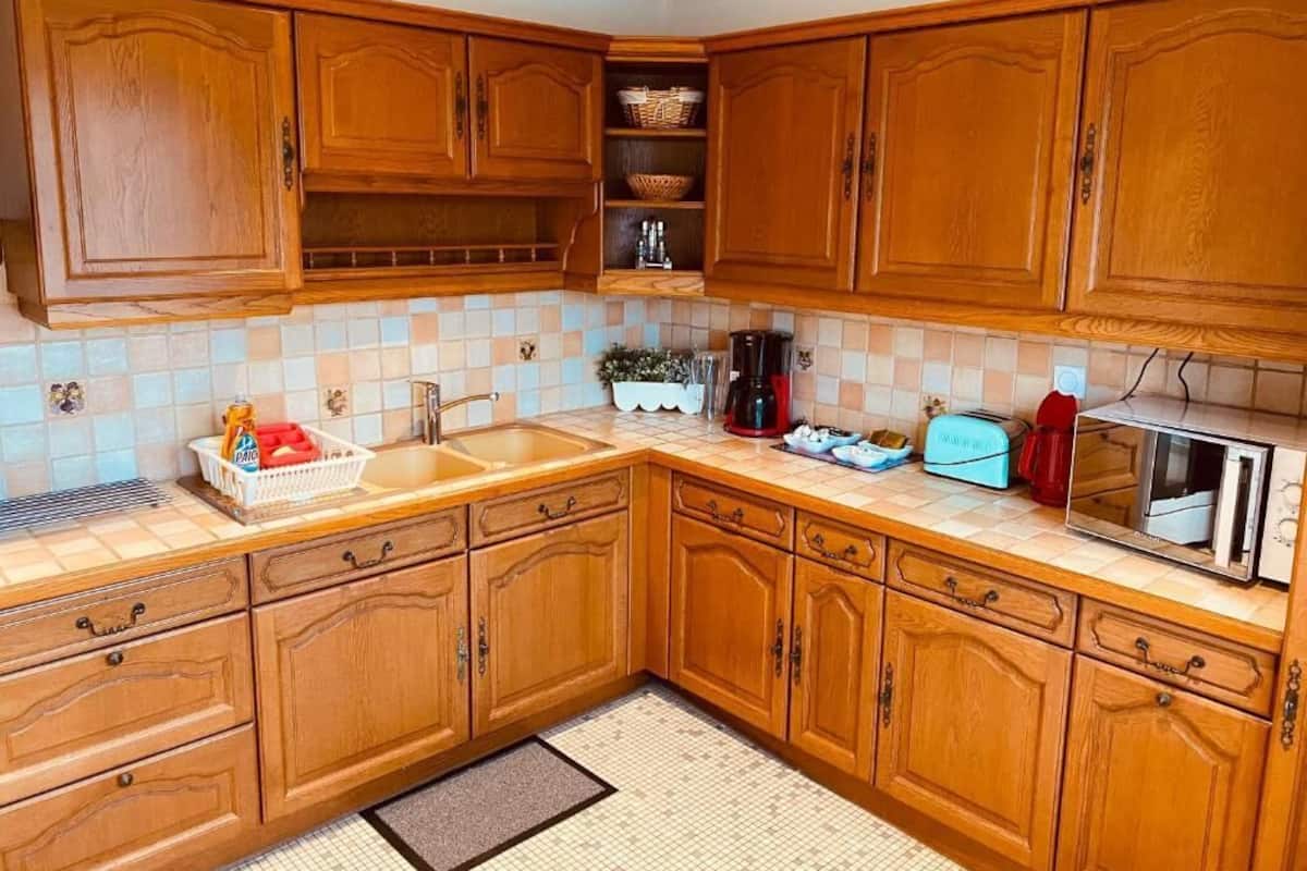 Eine Küche mit Holzschränken, einer gefliesten Spritzschutzwand, einem Spülbecken, einem Toaster und einer Mikrowelle.