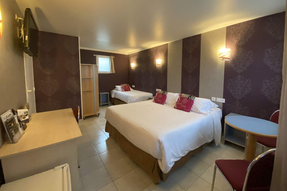 Ein Hotelzimmer mit zwei Betten, einem Schreibtisch, einem Stuhl, einem Kleiderschrank und einem kleinen Tisch.