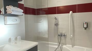 A modern bathroom with a glass-enclosed shower, a white bathtub, and a vanity with a towel rack.
