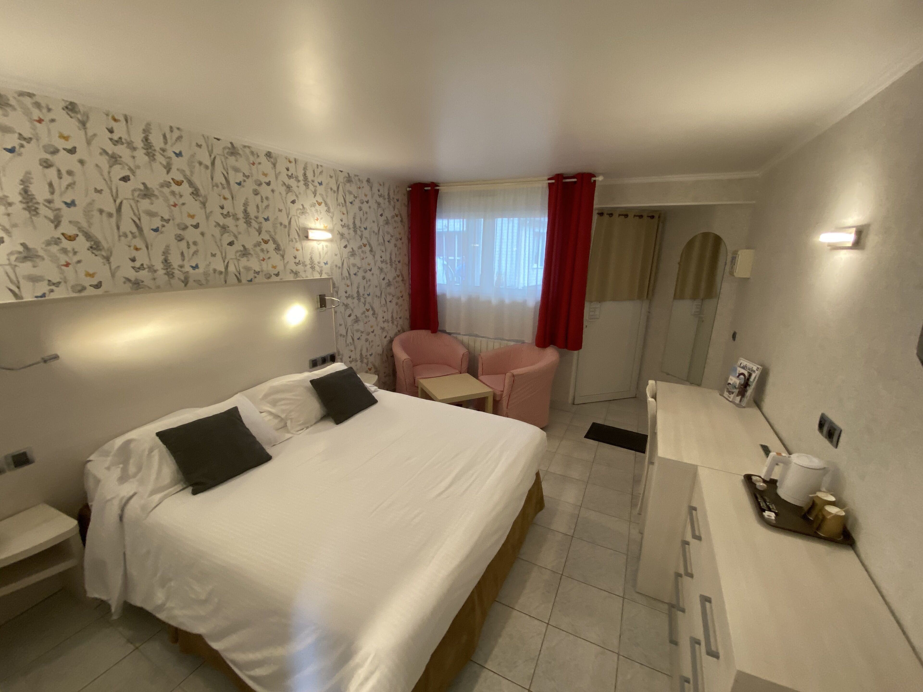 Una habitación de hotel con cama, escritorio, silla y una mesita.